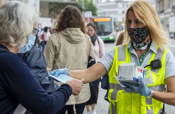 Eine Mitarbeiterin der Basler Verkehrs-Betriebe BVB verteilt Schutzmasken am Bahnhof SBB in Basel, am Montag, 6. Juli 2020. Das Schutzkonzept gegen das Coronavirus wurde angepasst: Alle Reisenden mues ...