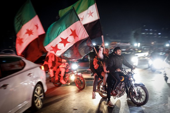 epa11771529 Syrians wave three-starred opposition flags as they celebrate the fall of the President Bashar al-Assad regime, at Umayyad Square, in Damascus, Syria, 11 December 2024. Syria&#039;s Milita ...