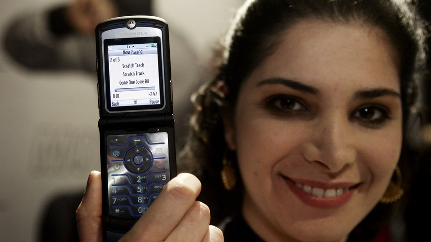 Motorola representative Nazee Hoglund from Liberty, Ill., holds a new Motorola RAZR V3i, at the Motorola booth Saturday, Jan. 7, 2006, at the International Consumer Electronics Show, CES, in Las Vegas ...