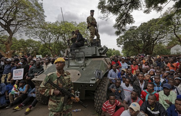 Army soldiers stand guard as protesters demanding President Robert Mugabe stands down gather on the road leading to State House in Harare, Zimbabwe Saturday, Nov. 18, 2017. In a euphoric gathering tha ...