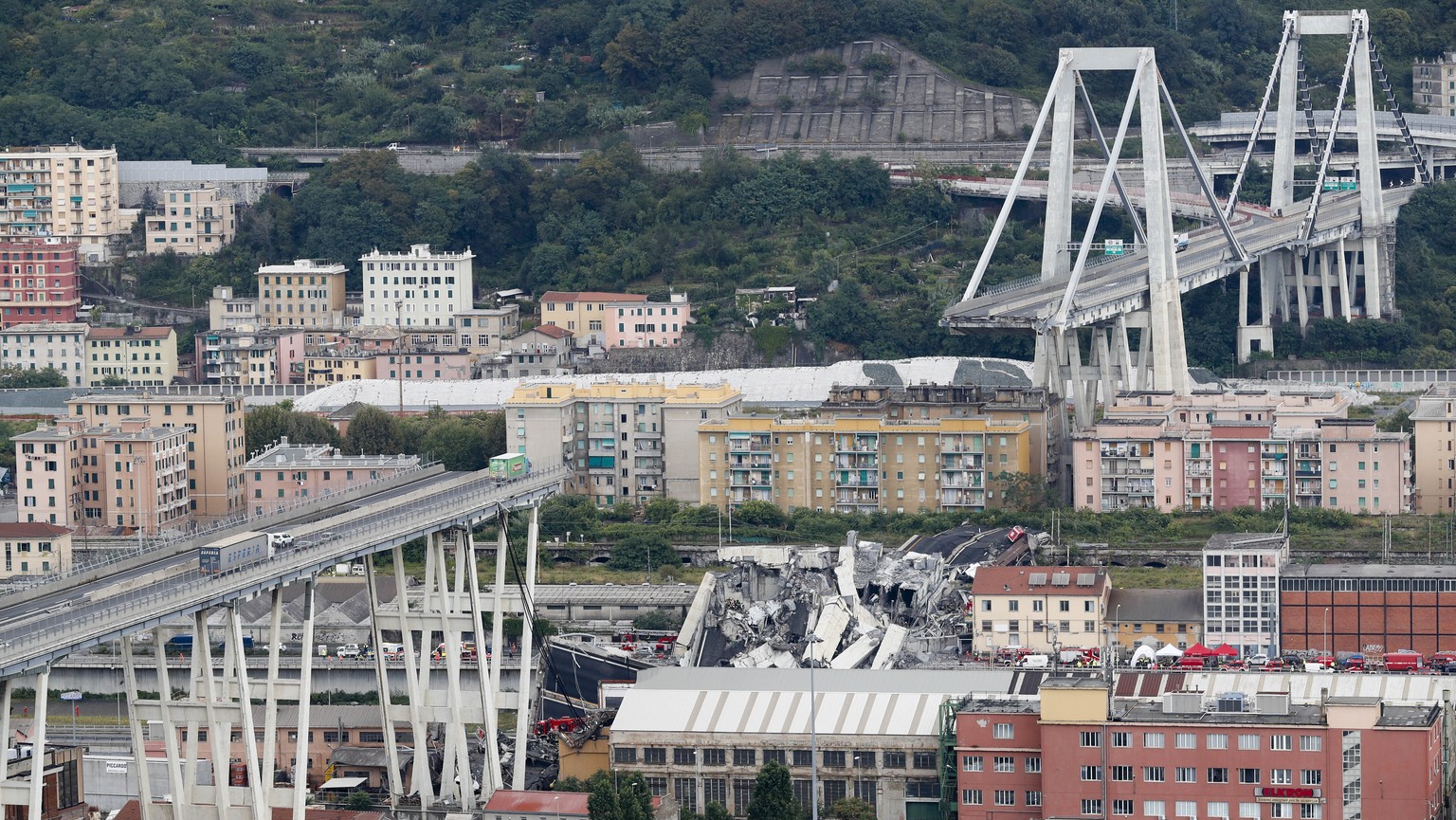 FILE - In this Tuesday, Aug. 14, 2018 file photo cars are blocked on the Morandi highway bridge after a section of it collapsed, in Genoa, northern Italy. Fifty-nine people went on trial Thursday, Jul ...