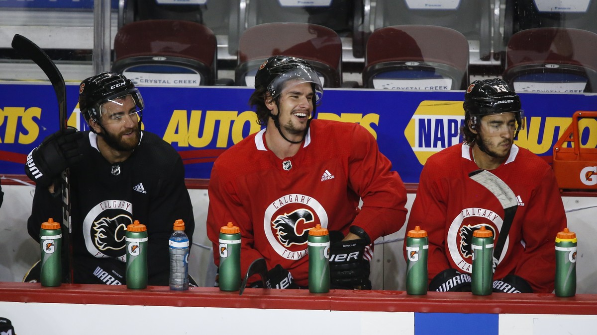 Calgary Flames' Sean Monahan, center, laughs with teammates T. J. Brodie, left, and Johnny Gaudreau during NHL hockey practice in Calgary, Alberta, Thursday, July 23, 2020. (Jeff McIntosh/The Can ...