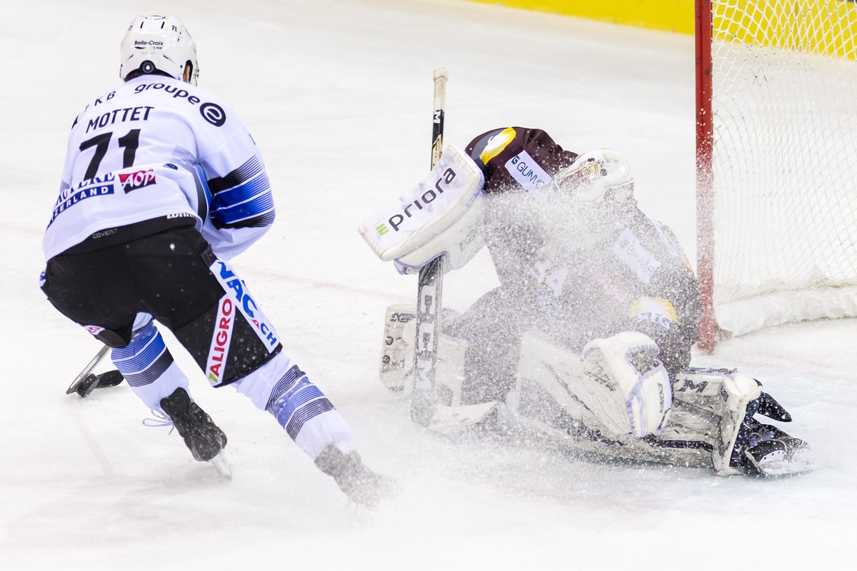 Le joueur fribourgeois, Killian Mottet, gauche, a la lutte pour le puck avec le gardien Genevois, Gauthier Descloux, droite, lors du match du championnat suisse de hockey sur glace de National League  ...