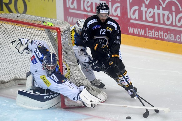 Ambri&#039;s goalkeeper Benjamin Conz, left, fights for the puck with Lugano’s player Luca Cunti, right, during the preliminary round game of National League during the game between HC Lugano and HC A ...