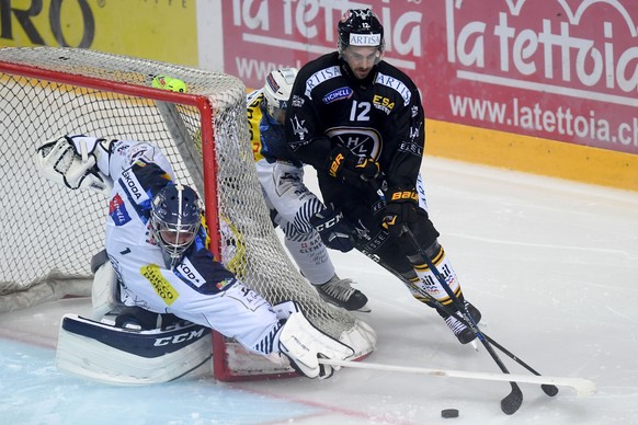 Ambri&#039;s goalkeeper Benjamin Conz, left, fights for the puck with Luganoâs player Luca Cunti, right, during the preliminary round game of National League during the game between HC Lugano and HC ...