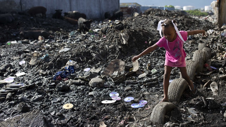 A girl returns from a designated area where neighbors use the bathroom outside, in the Cite Soleil slum of Port-au-Prince, Haiti, Tuesday, Nov. 21, 2017. The Trump administration said it is ending a t ...