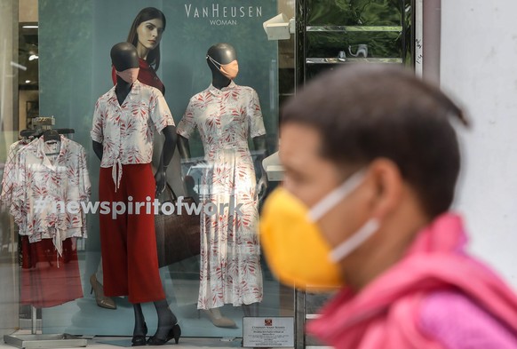 epa08517848 Mannequins with protective masks are kept inside a garments showroom as an Indian man wearing a protective face mask walks in New Delhi, India, 30 June 2020. Countries around the world are ...