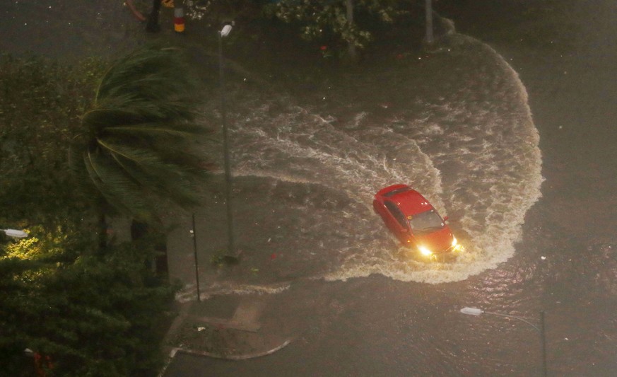 FILE - In this Saturday, Sept. 15, 2018, file photo, a vehicle negotiates a flooded street in Manila as Typhoon Mangkhut continues to batter the northeastern Philippines before dawn in Manila, Philipp ...