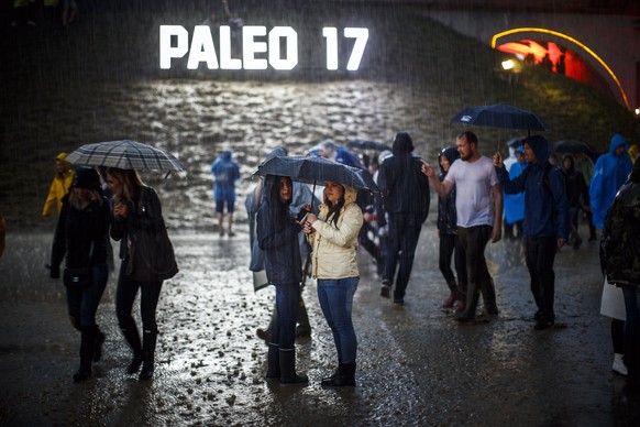 epa06102931 Festival goers wait under their umbrellas during a heavy rain storm at the 42nd Paleo Festival, in Nyon, Switzerland, 21 July 2017 (issued 22 July 2017). The event runs from July 18 to 23. ...