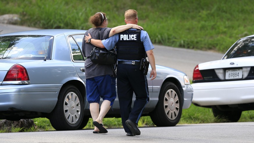 Kansas City, Kan., police officer Brad Lightfoot, right, walks Susan Goble to the shooting scene of a police officer in Kansas City, Kan., Tuesday, July 19, 2016. Goble knows the family of the fallen  ...