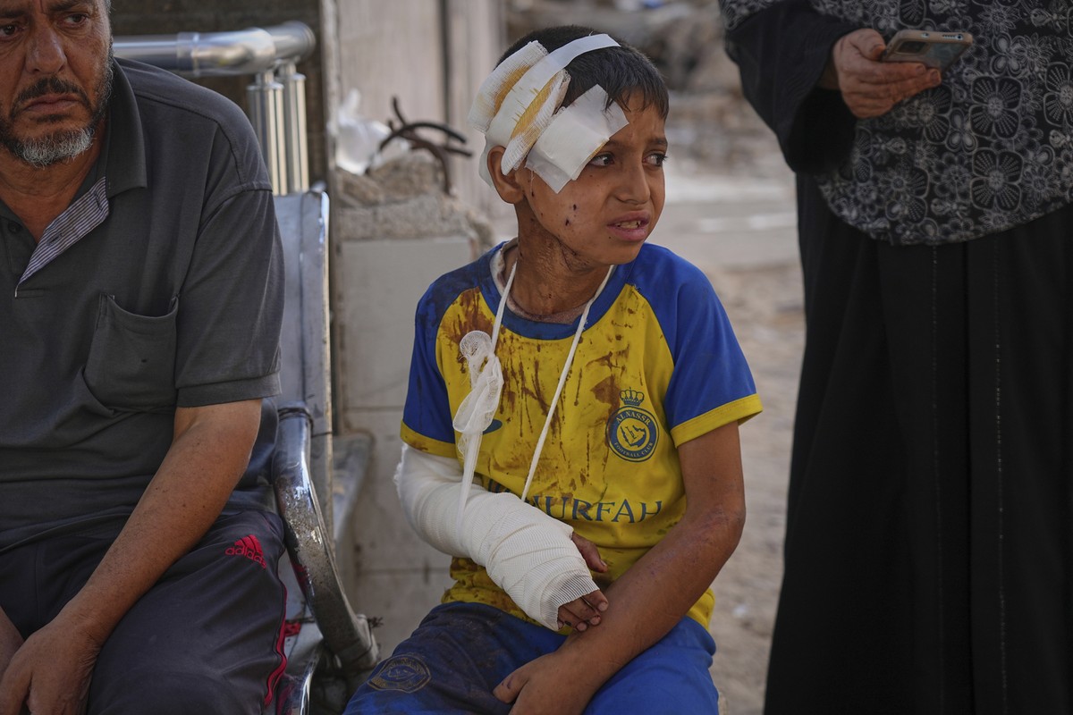 Hamam Al-Farani, sits along with other family members as the body of his father, Alaa, killed in an Israeli army strike that also injured the boy, is prepared for burial at Shifa hospital in Gaza City ...