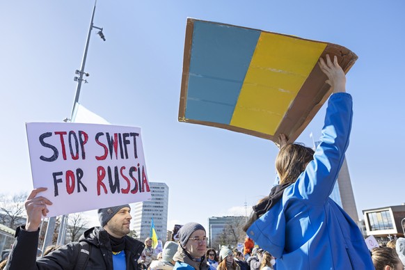 epa09786216 A demonstrator holds a sign that reads &#039;Stop Swift for Russia&#039; while protesting against Russia&#039;s massive military operation against Ukraine during a rally on the place of th ...