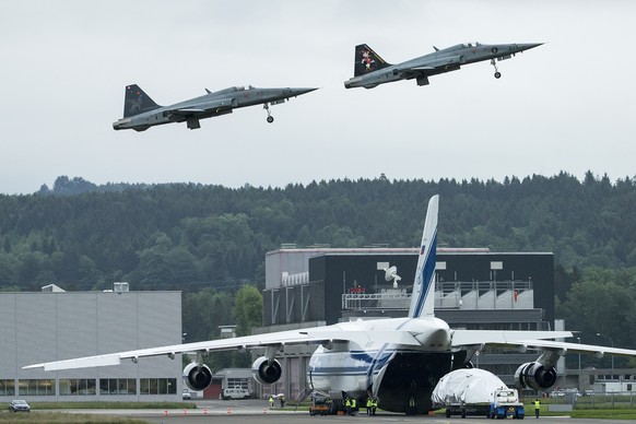 Zwei F-5 Tiger fliegen ueber das Frachtflugzeug des Typs Antonov An-124, welches beladen wird mit Raketenteilen der Ruag, fotografiert auf dem Militaerflugplatz Emmen am Dienstag, 15. Mai 2018. (KEYST ...