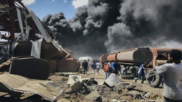 FILE - People are seen in front of clouds of black smoke from fires in the aftermath at the scene of an airstrike in Mekele, the capital of the Tigray region of northern Ethiopia on Oct. 20, 2021. The ...