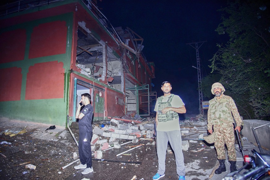 Security force officials stand outside a damaged building at a site of a suspected Indian missile attack near Muzaffarabad, the capital of Pakistan controlled Kashmir, in Wednesday, May 7, 2025. (AP P ...
