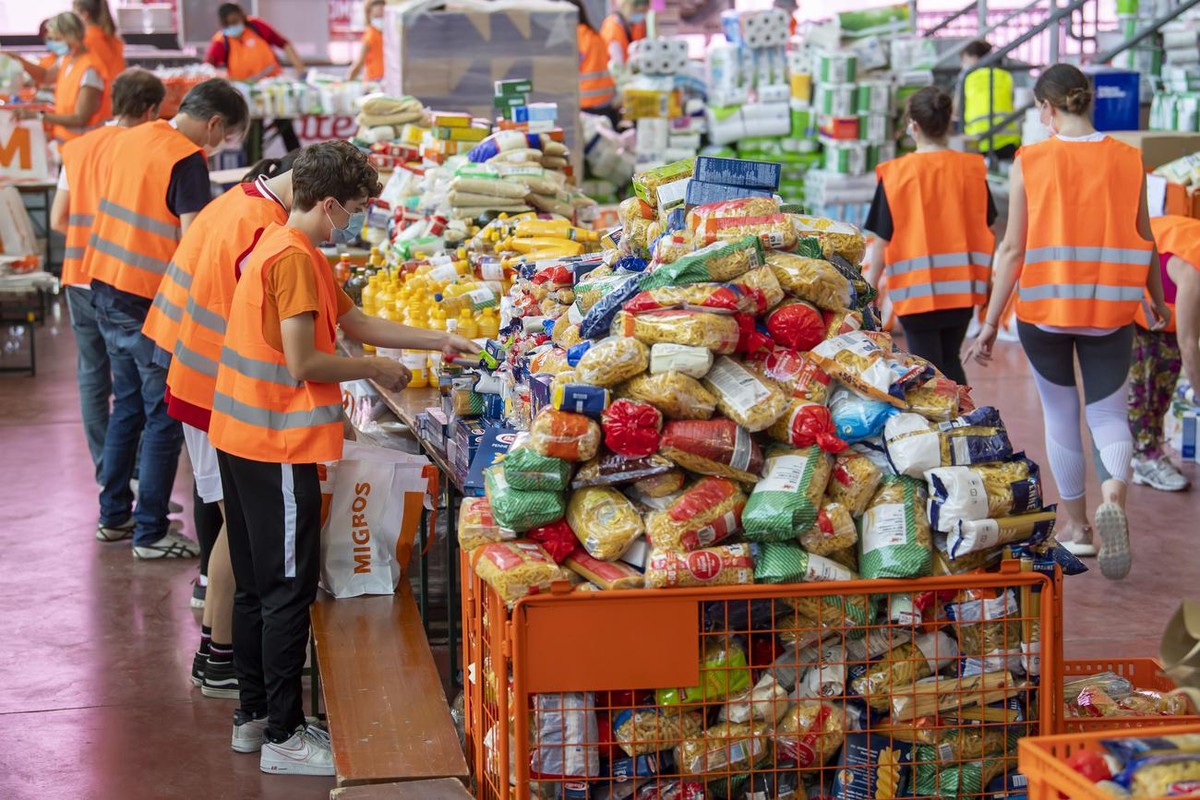 Des benevoles s'affairent autour de la preparations des sacs alimentaires, organisee par la Caravane de la Solidarite Geneve, ce vendredi 22 mai 2020 a la patinoire des Vernets a Geneve. Cette de ...