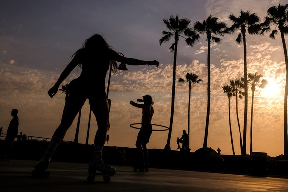 People are silhouetted as they workout during sunset on Wednesday, June 16, 2021, in the Venice Beach section of Los Angeles. An unusually early and long-lasting heat wave brought more triple-digit te ...