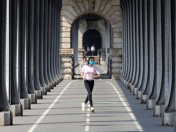 Eine Frau, die eine Schutzmaske tr�gt, w�hrend sie am zw�lften Tag einer coronabedingten Abriegelung in Paris joggt. Seit Freitagmorgen (28. August) m�ssen die Menschen �berall in Paris aufgrund er Co ...