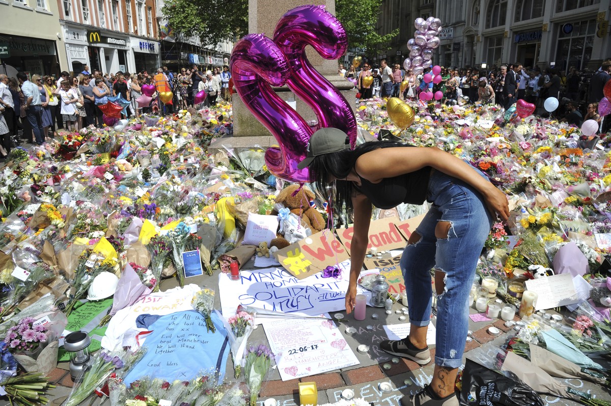 A young woman views of flower tributes for the victims of Monday's explosion at St Ann's square in central Manchester, England Thursday May 25 2017. More than 20 people were killed in an exp ...