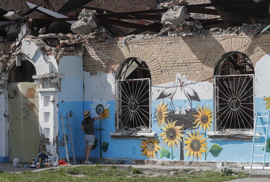 epa10133725 Street artist Olena Yanko paints sunflowers onto a wall of a damaged centre of social and cultural activities building in the city of Irpin near Kyiv, Ukraine, 22 August 2022 amid the Russ ...