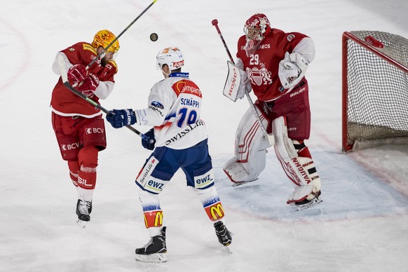 Le joueur zuerichois Reto Schaeppi, centre, lutte pour le puck avec le top scorer lausannois Jonas Junland, gauche, et le gardien lausannois Luca Bolthauser, droite, lors de la rencontre du championna ...