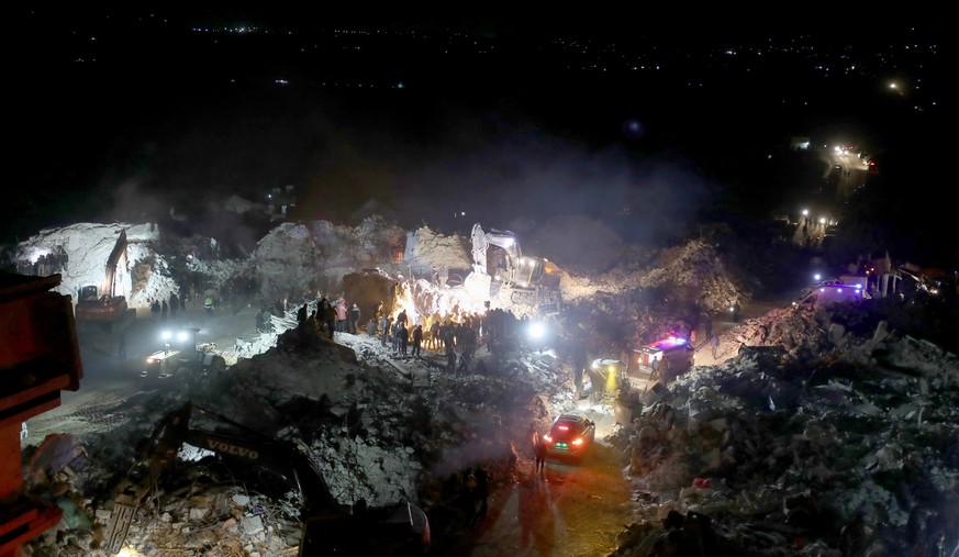 epaselect epa10454066 Rescuers from the White Helmets group, the Syrian Civil Defense operating in the area, and people look for survivors under the rubble of a collapsed building, after an earthquake ...