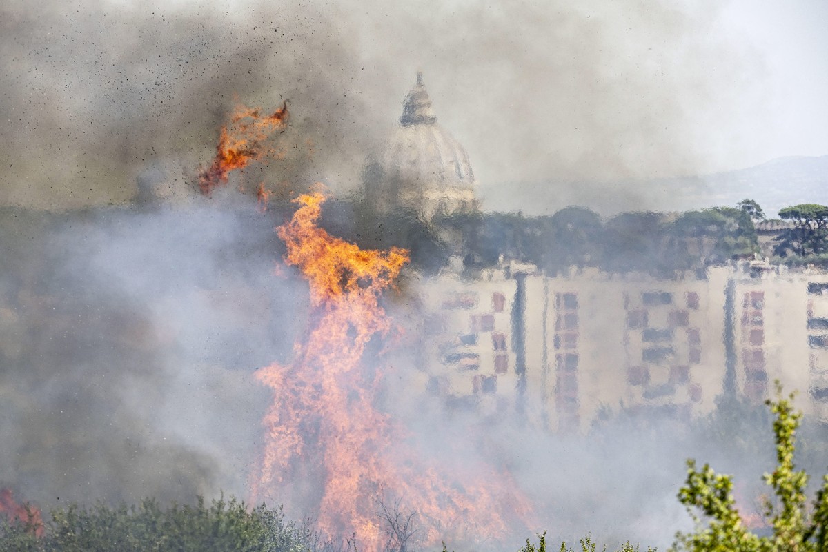 epa10051631 The dome of St. Peter's Basilica is seen through smoke rising from a fire that erupted in a park area in the north of Rome, Italy, 04 July 2022. The fire, fueled by hot winds, affecte ...