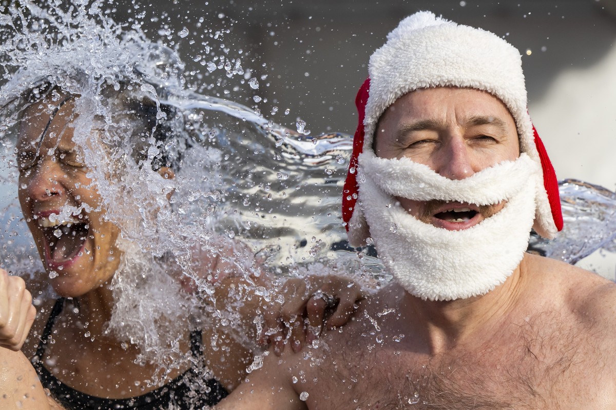 epaselect epa11788526 Participants of the 86th edition of the annual Christmas swimming 'Coupe de Noel' are sprayed with water before jumping into Lake Geneva, in Geneva, Switzerland, 21 Dec ...
