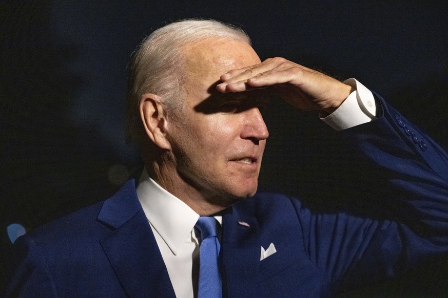 epa10075673 US President Joe Biden shields his eyes from the bright floodlight as he answers a reporter���s question on the South Lawn of the White House in Washington, DC, USA, after returning from a ...