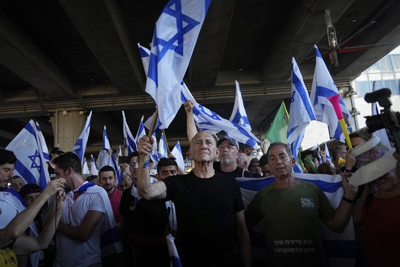 Former Israeli Prime Minister Ehud Olmert, center, waves the national flag during a protest against plans by Prime Minister Benjamin Netanyahu&#039;s government to overhaul the judicial system, at Ben ...
