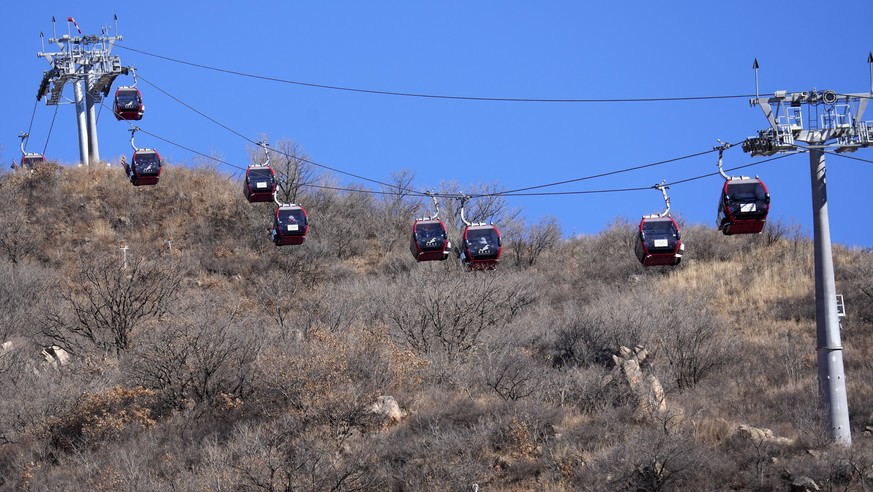 Gondolas travel up the mountain alongside the alpine skiing course devoid of snow at the 2022 Winter Olympics, Wednesday, Feb. 2, 2022, in the Yanqing district of Beijing. (AP Photo/Luca Bruno)