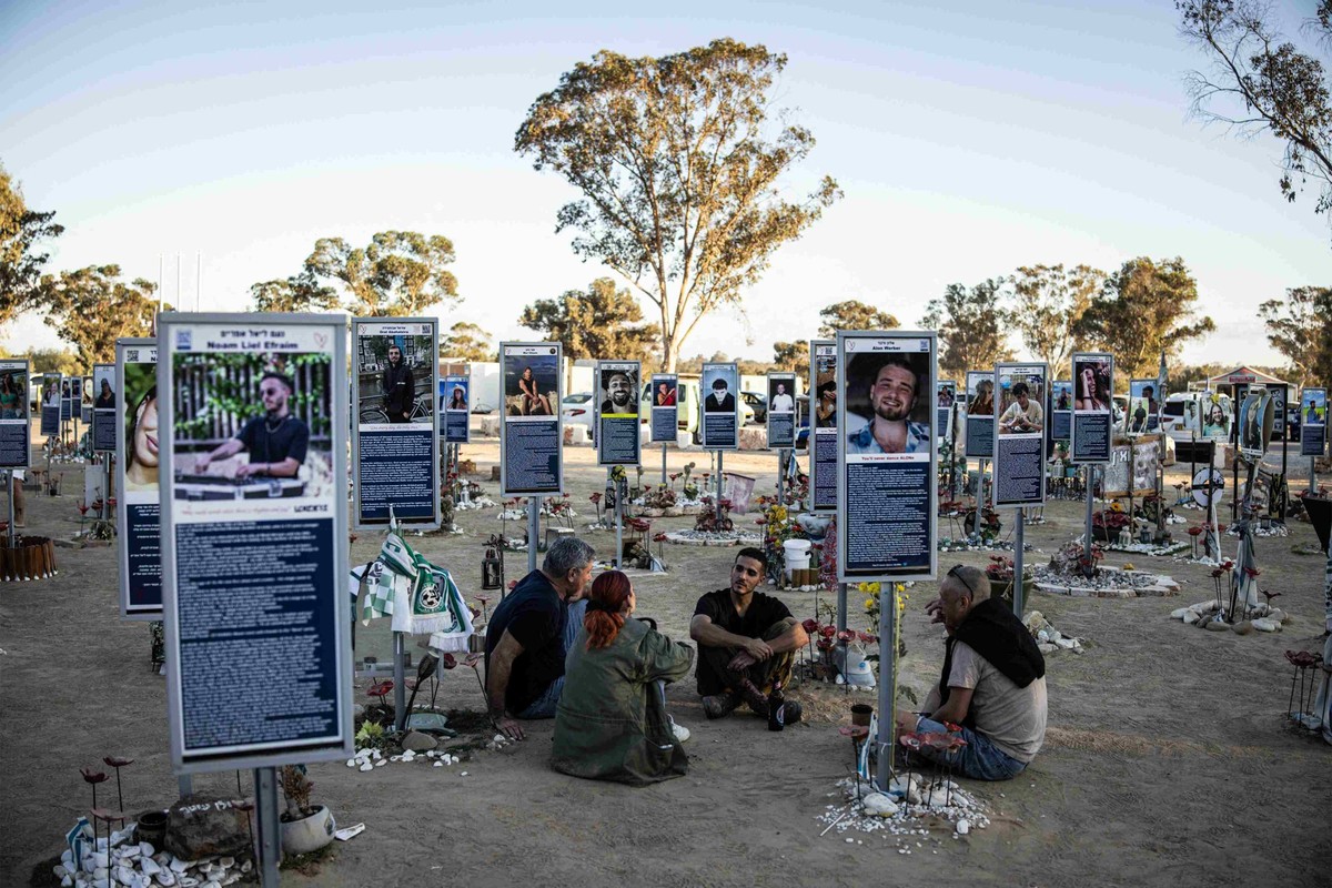 Une famille est assise devant un mémorial dédié à l'une des victimes des attentats du 7 octobre 2023, sur le site du festival Nova à Reim, dans le sud d'Israël, à l'occasion du deuxième ...