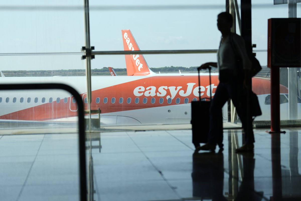epa10116908 A man walks past an EasyJet plane at El Prat airport, Barcelona, Spain, 12 August 2022. The first day of the EasyJet pilots' strike in August has caused cancellations at El Prat and i ...