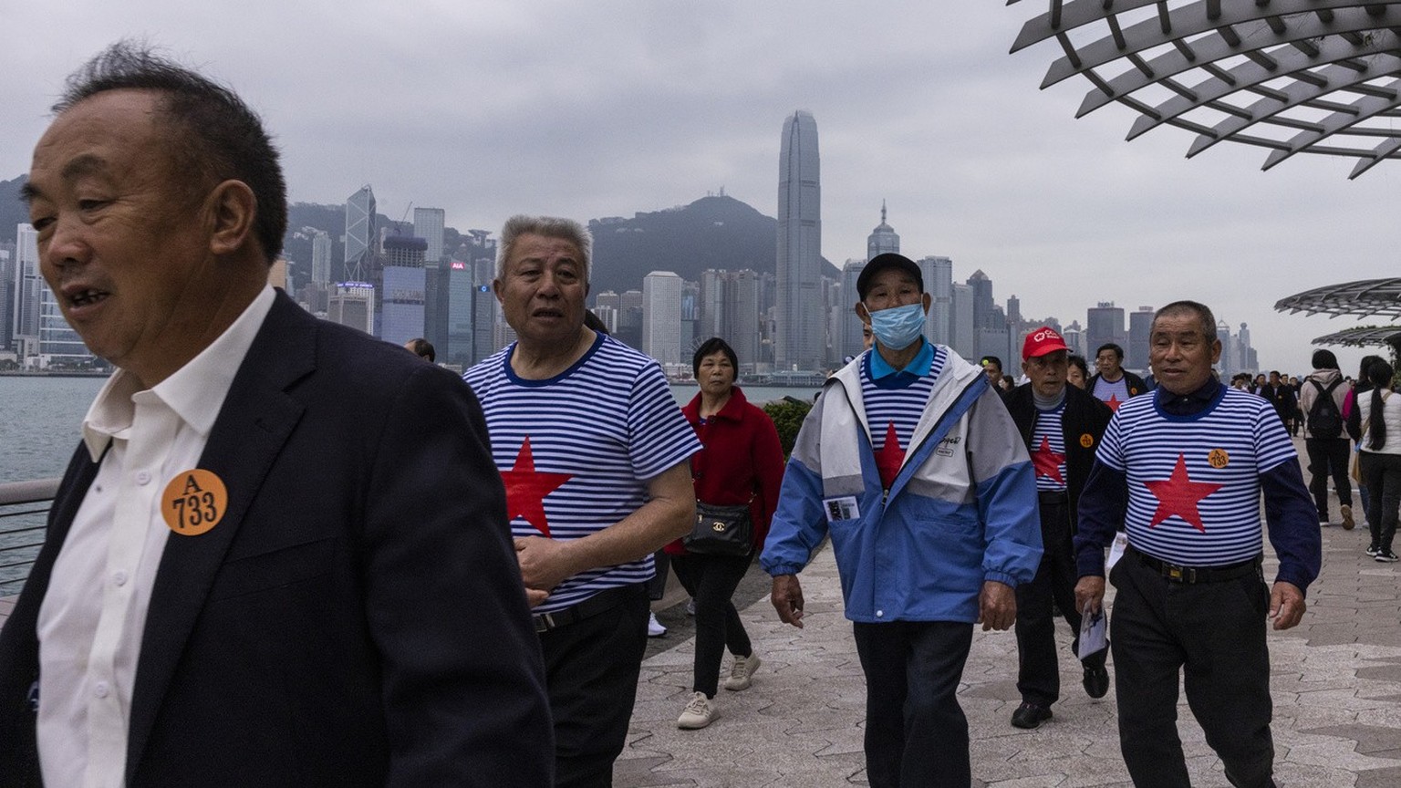Mainland Chinese tourists on a budget tour walk along a promenade in Hong Kong, Monday, April 10, 2023. (AP Photo/Louise Delmotte)