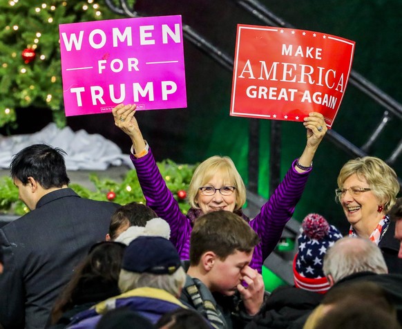 epa05674596 A woman holds up signs while waiting for the start of a Thank You Tour rally with US President elect Donald Trump and US Vice president elect Mike Pence at the Wisconsin State Fair Exposit ...