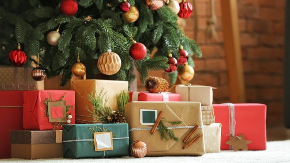 Schöne Weihnachtsgeschenke unter Tannenbaum auf dem Boden im Zimmer