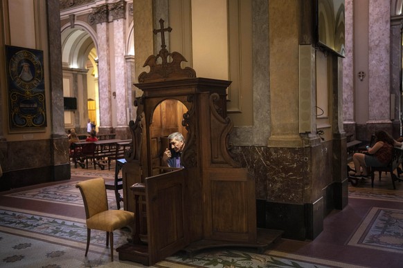 A priest listens to a parishioner confess at the Cathedral in Buenos Aires, Argentina, Thursday, Dec. 21, 2023. (AP Photo/Rodrigo Abd)