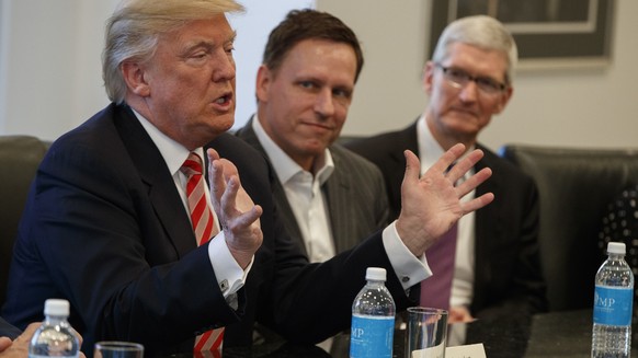 Apple CEO Tim Cook, right, and PayPal founder Peter Thiel, center, listen as President-elect Donald Trump speaks during a meeting with technology industry leaders at Trump Tower in New York, Wednesday ...