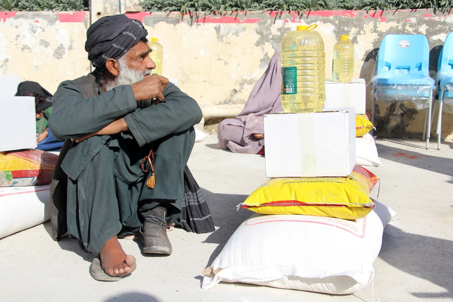 epa11100904 Afghan refugees, who have returned from neighboring Pakistan, receive food items donated by the Qatar Red Crescent in Kandahar, Afghanistan, 24 January 2024. Pakistan has been implementing ...