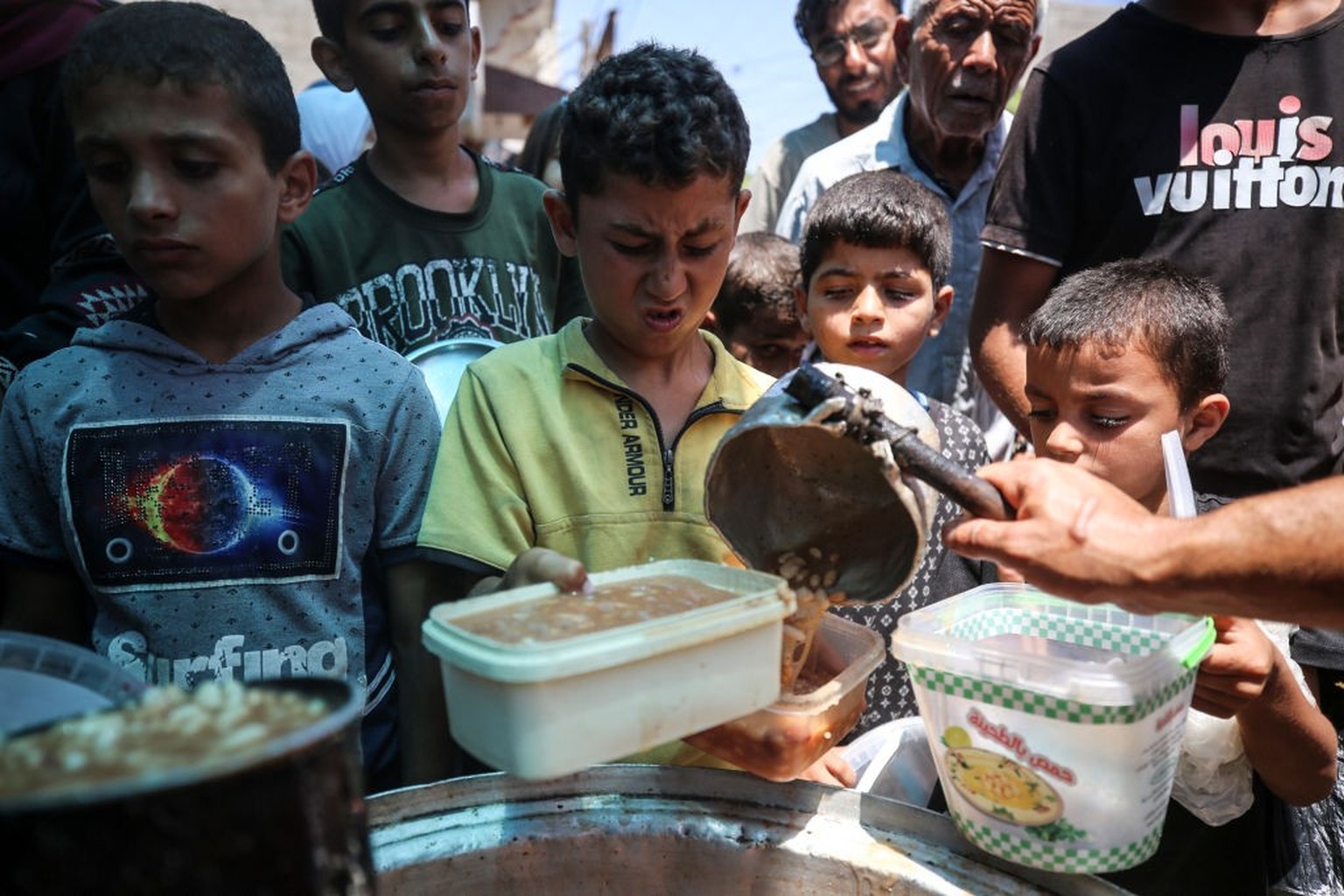 Palestinians are queuing for meal rations at a communal food distribution point in Deir al-Balah in the besieged Gaza Strip on June 10, 2024, amid the ongoing conflict between Israel and the Palestini ...