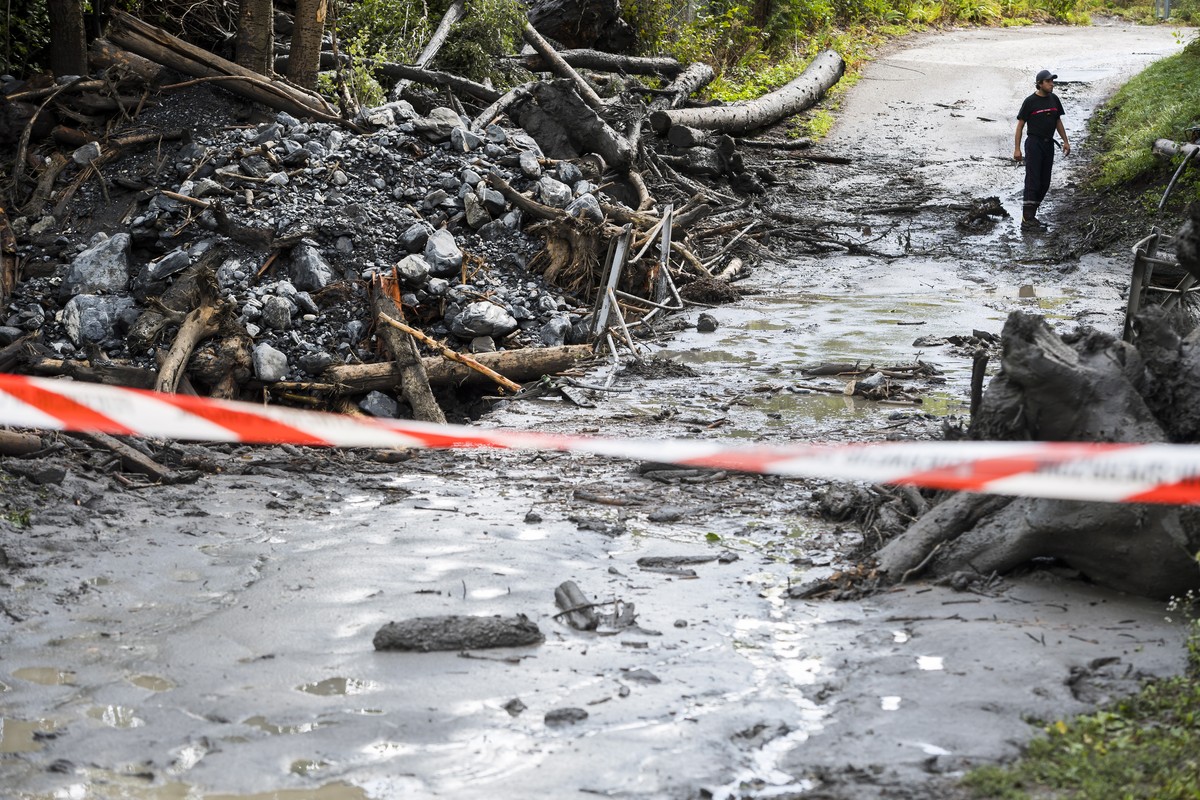 epa07770015 Two firefighters are securing the banks of the Losentse River in Chamoson, canton Valais, Switzerland, 12 August 2019. Search efforts continued on the day in Chamoson for two missing perso ...