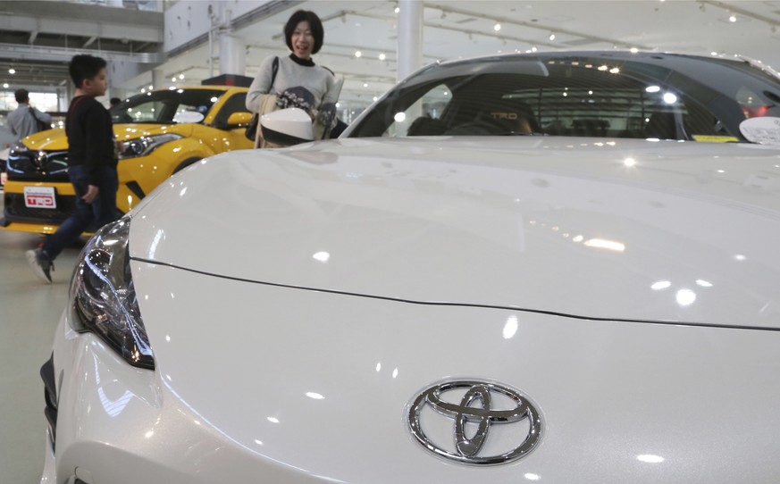 In this Nov. 13, 2017 photo, visitors take a look at a Toyota car at its showroom in Tokyo. Toyota plans to offer more than 10 purely electric vehicle models in its lineup by the early 2020s, marking  ...