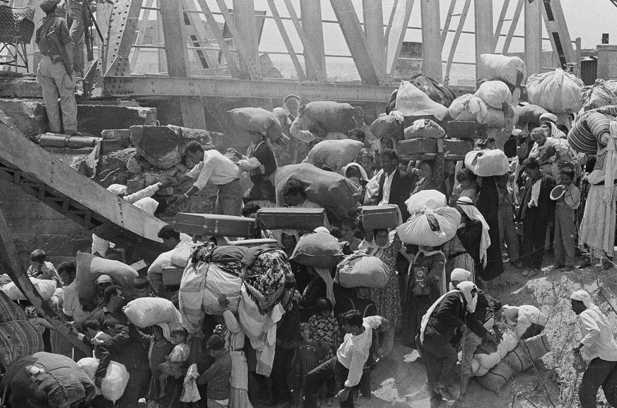 Palestinian refugees carry their belongings as they prepare to cross the wrecked Allenby Bridge over the Jordan River from the Israeli-occupied section of Jordan, June 22, 1967. Many of the refugees s ...