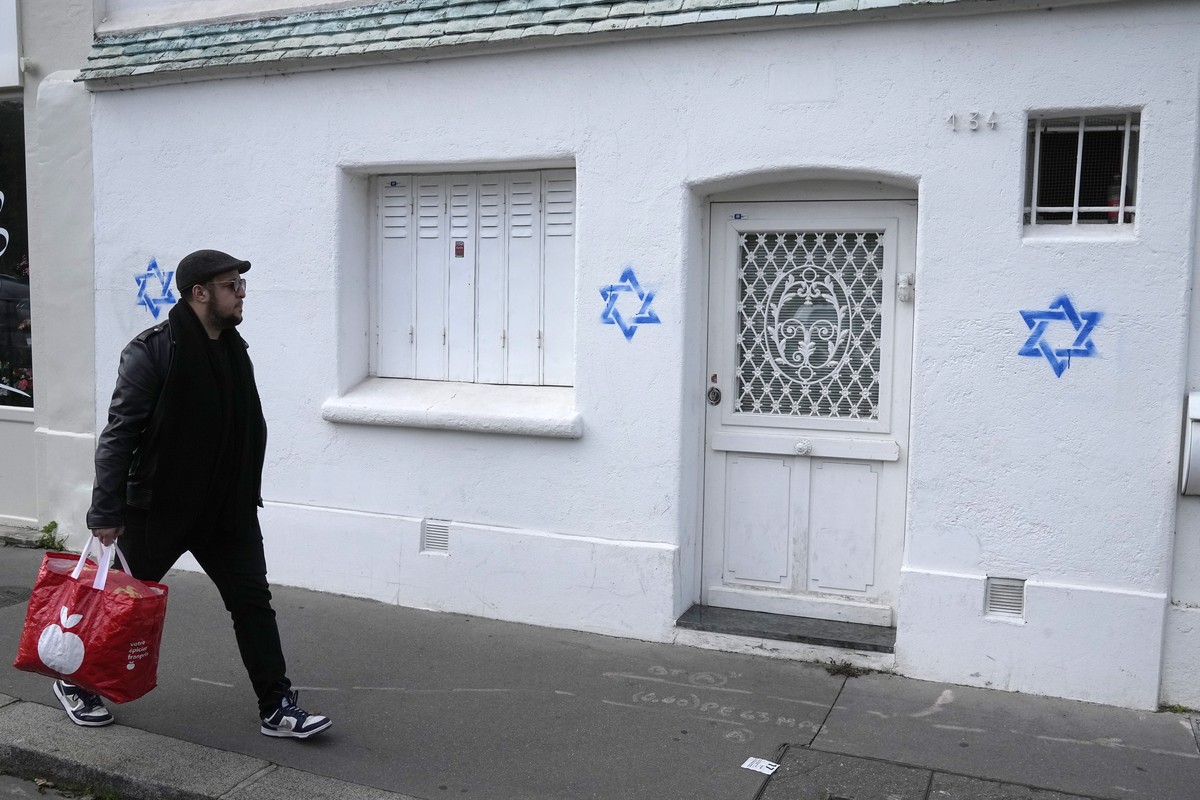 A man walks by Stars of David tagged on a wall Tuesday, Oct. 31, 2023 in Paris. Paris police chief Laurent Nunez described the graffiti as anti-Semitic and said police are investigating. (AP Photo/Mic ...