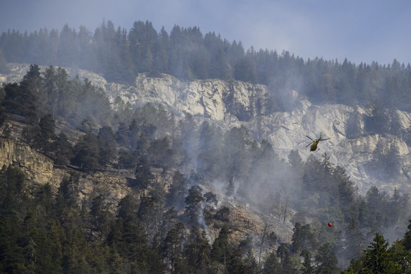 A helicopter pours water on the still burning forest above the communes of Bitsch and Ried-Moerel, in Bietsch, Switzerland, Tuesday, July 18, 2023. Swiss authorities have temporarily shut the airspace ...