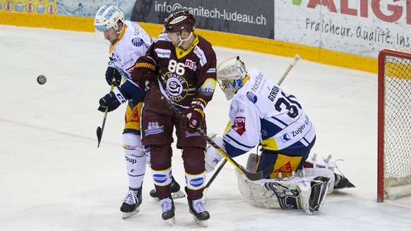 Zug&#039;s defender Livio Stadler, left, vies for the puck with $Geneve-Servette&#039;s center Joel Vermin #86 part Zug&#039;s goaltender Leonardo Genoni, right, during the second leg of the National  ...