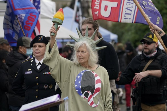 A person dressed as Lady Liberty wears a shirt with the letter Q, referring to QAnon, as protesters take part in a protest, Wednesday, Jan. 6, 2021, at the Capitol in Olympia, Wash., against the count ...