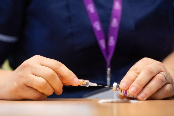 epa08931900 A nurse prepares a dose of the Oxford/AstraZeneca Covid-19 vaccine at the NHS vaccine mass vaccination centre that has been set up in the grounds of Epsom Race Course, in Surrey, Britain 1 ...