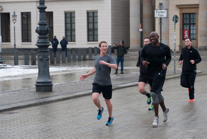 epa05179936 Facebook founder Mark Zuckerberg (L) runs across Pariser Platz square with bodyguards in Berlin, Germany, 25 February 2016. Mark Zuckerberg, founder and chief executive of the social netwo ...