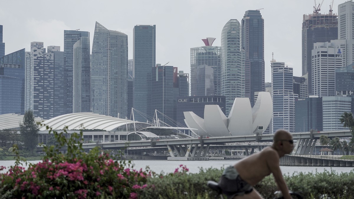 epa09013609 A cyclist rides past the skyline of the financial district in Singapore, 15 February 2021. Singapore has reported a 5.4 percent contraction in its economy in 2020, above advanced estimates ...